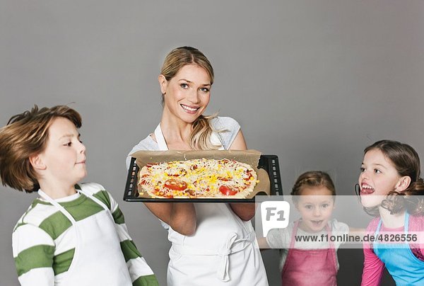 Mutter und Kinder mit Pizza im Backblech