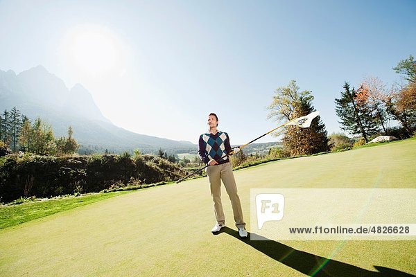 Italien,  Kastelruth,  Mittlerer Erwachsener Mann mit Golfflagge auf dem Golfplatz
