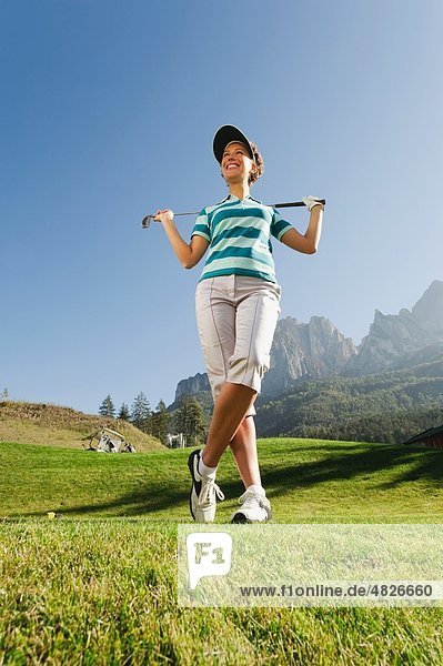 Italien  Kastelruth  Mittlere erwachsene Frau mit Golfschläger auf dem Golfplatz