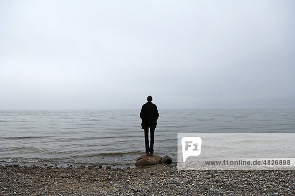 Junger Mann steht bei trübem Wetter an der Ostsee  Groß Schwansee  Mecklenburg-Vorpommern  Deutschland  Europa