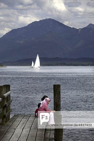 Muslim woman sitting on jetty Pier at Prien Stock  lake Chiemsee  Chiemgau  Upper Bavaria  Germany  Europe