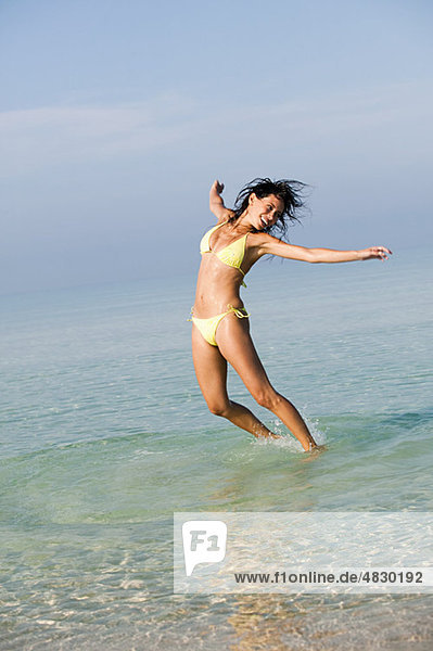 Junge Frau beim Springen im Meer