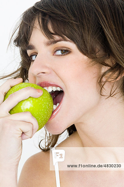 Porträt einer jungen brünetten Frau beim Apfelessen