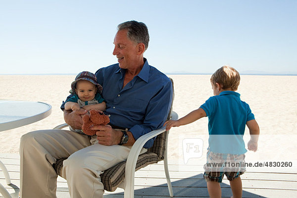 Großvater sitzend mit zwei Enkeln
