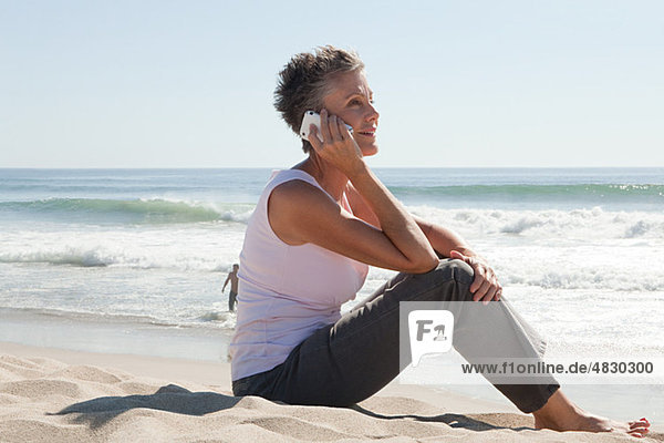 Senior woman using cell phone on beach
