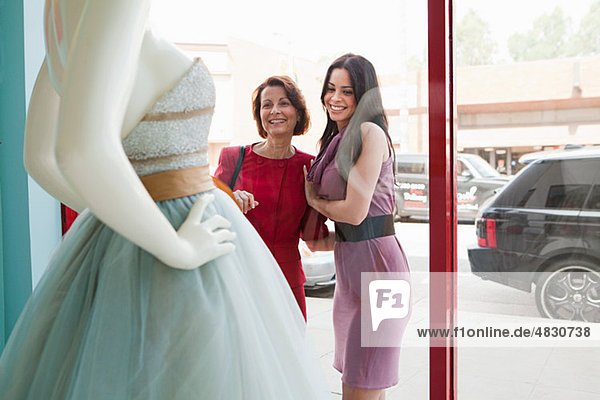 Mutter und Tochter beim Anblick des Hochzeitskleides im Schaufenster
