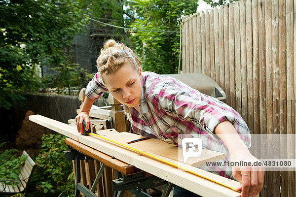 Woman measuring plank of wood