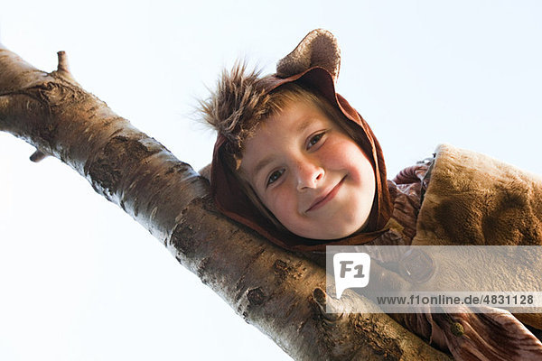 Junge verkleidet als Bär auf Baumzweig