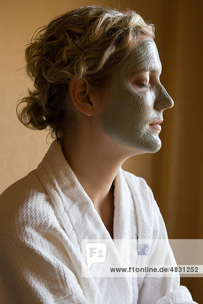 Young woman with mud mask on face