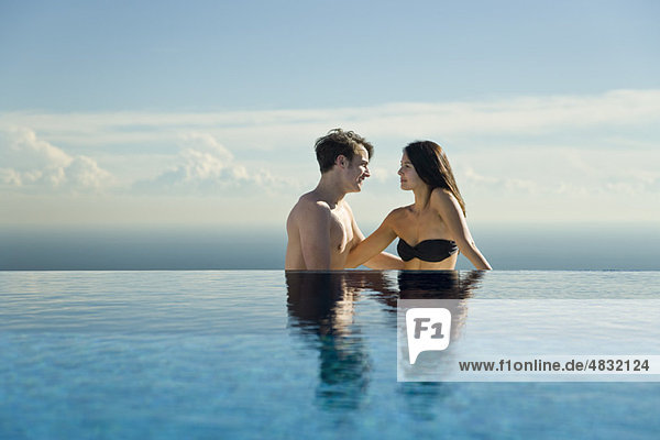 Couple relaxing by infinity pool
