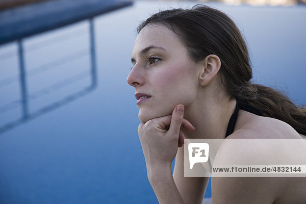 Frau am Pool  in Gedanken wegschauend