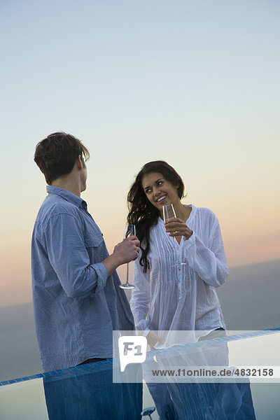 Couple standing at edge of infinity pool  enjoying champagne