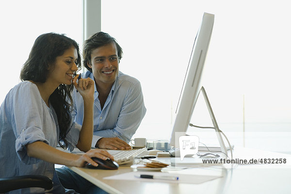 Couple looking at desktop computer together  both smiling