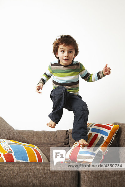 Junge springt auf Sofa