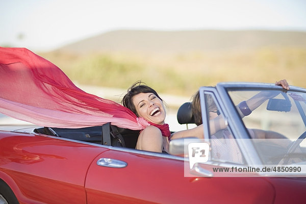 Frau mit langem roten Schal im Auto unterwegs