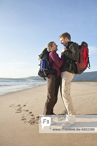 Backpacking couple hugging at beach