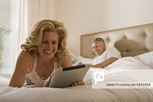 Woman using tablet computer on bed