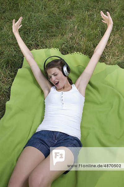 Happy young woman listening to music in meadow
