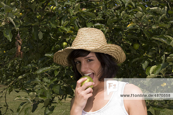 Young woman eating apple from tree  portrait