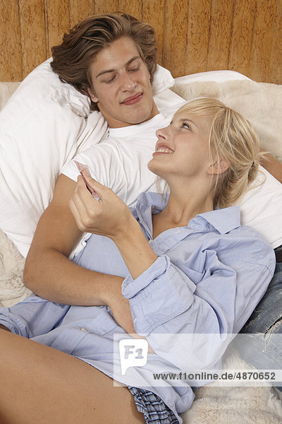 Junges Paar mit Kondom im Bett