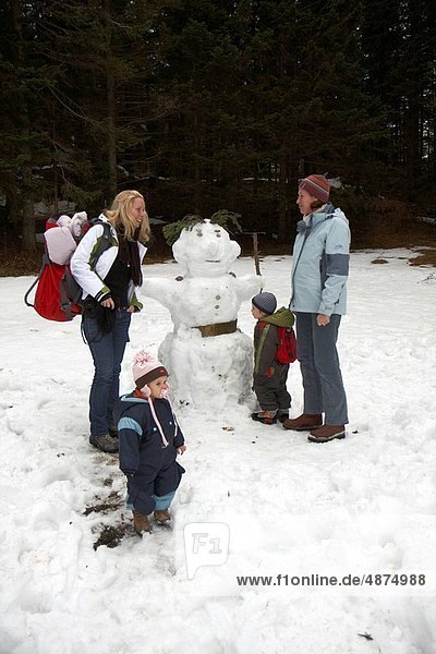 two female friends with children having fun building a snow_man
