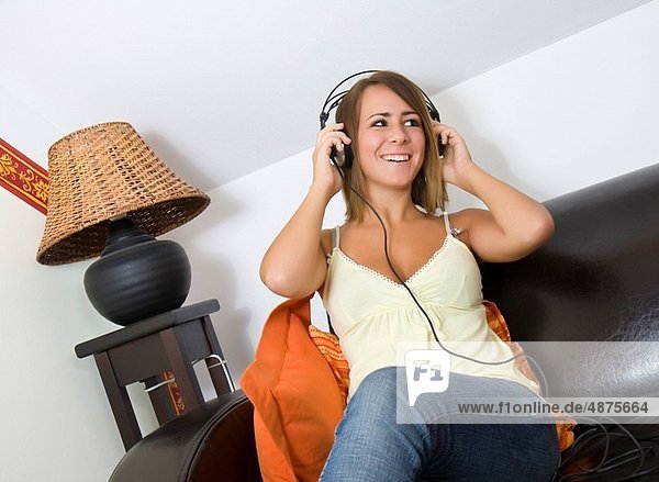girl sitting on sofa  listening to music via headphones
