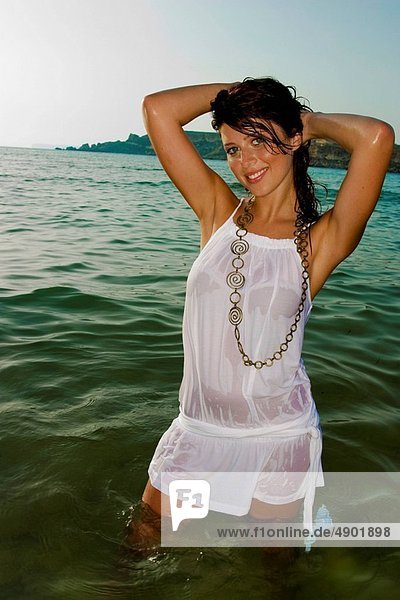 A sexy young woman wearing a wet white dress in the water