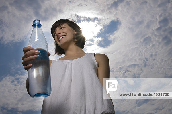 Junge Frau im Freien hält eine Wasserflasche