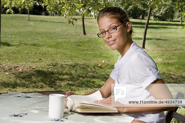 Junge Frau liest ein Buch im Freien