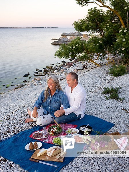reifes Paar mit Picknick am Strand