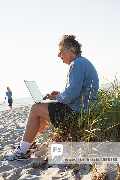 ältere Frau using Laptop am Strand