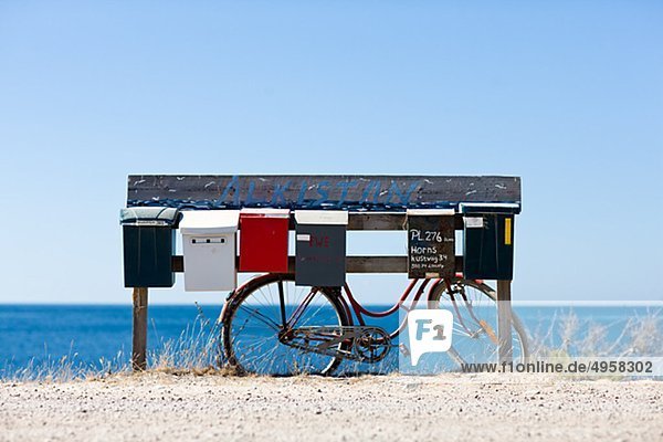 Briefkästen und Fahrrad mit Meer im Hintergrund