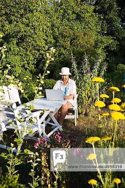 Senior Senioren benutzen Frau Notebook Garten