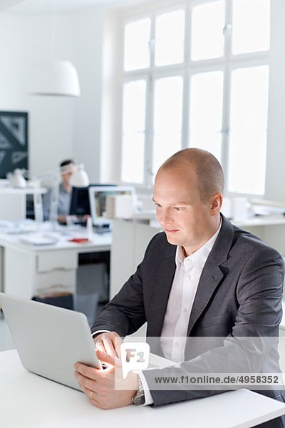 Man sitting in office using laptop