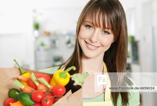 Frau steht in der Küche mit Gemüsebeutel