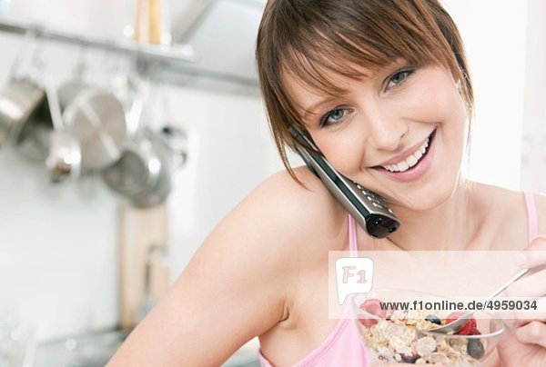 Woman eating fruit muesli with on the phone