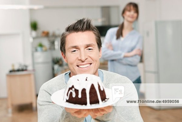Man holding cake in domestic kitchen