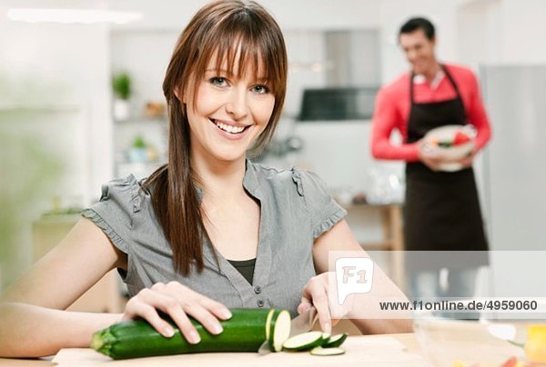 Woman chopping cucumber in kitchen