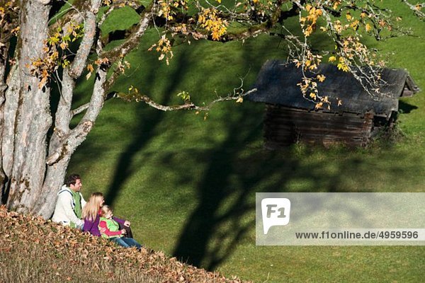 Österreich  Salzburg  Flachau  Familie sitzend auf Herbstwiese