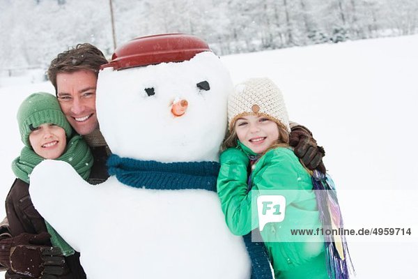 Österreich  Salzburg  Hüttau  Vater und Kinder mit Schneemann  lachend