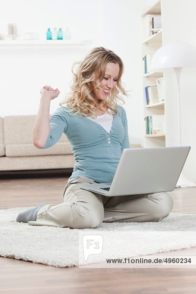 Woman sitting on floor and using laptop  laughing