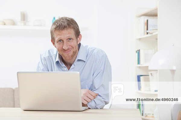Man using laptop at home  smiling  portrait