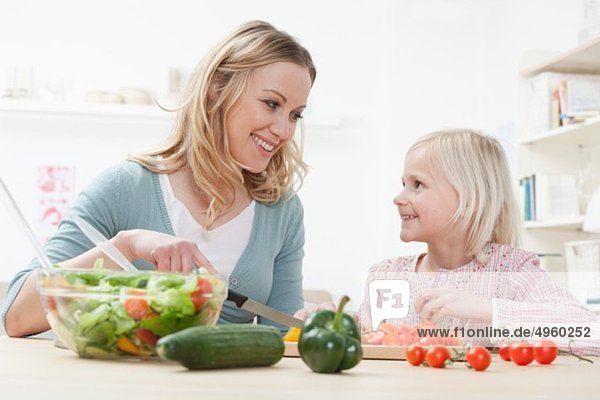 Deutschland  Bayern  München  Mutter und Tochter kochen Salat  lächelnd