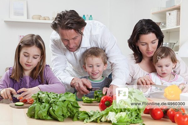 Germany  Bavaria  Munich  Mother and father helping kids to prepare salad
