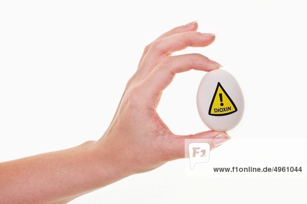 Menschliche Hand hält Ei mit Warnzeichen für Dioxin