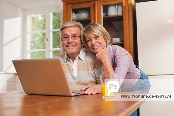 Deutschland  Kratzeburg  Seniorenpaar mit Laptop  lächelnd  Portrait