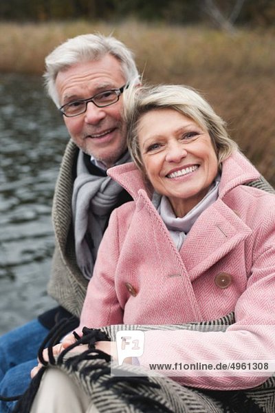 Deutschland  Kratzeburg  Seniorenpaar auf Strandpromenade sitzend  lächelnd  Portrait