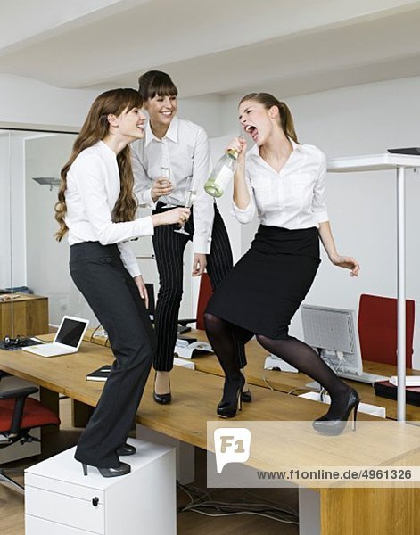 Young women having fun with sparkling wine in office