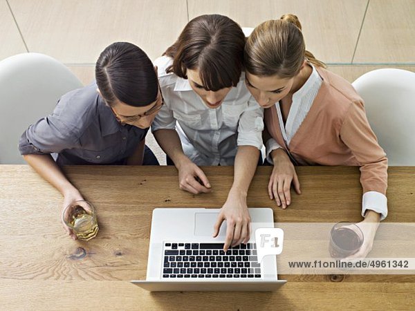 Junge Frauen nutzen Laptop und diskutieren im Büro