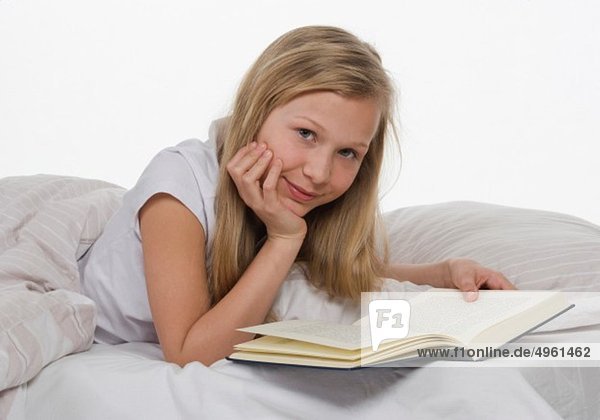 Mädchen auf dem Bett liegend mit Buch  Portrait
